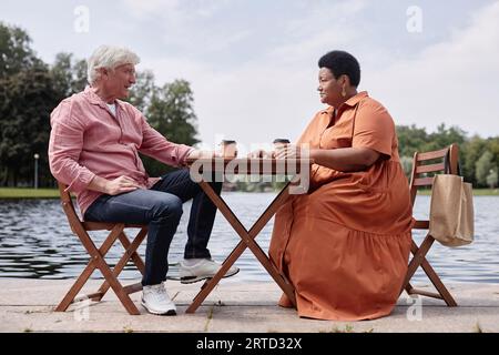 Portrait in voller Länge eines multiethnischen Seniorenpaares, das im Café im Freien ein Date genießt Stockfoto
