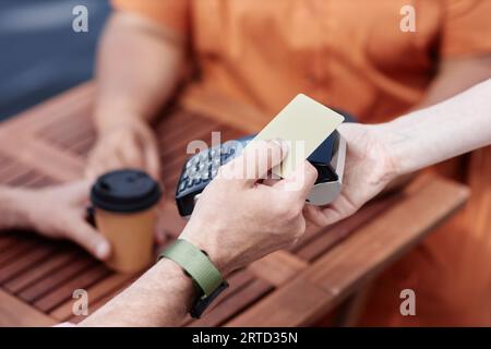 Nahaufnahme einer nicht erkennbaren Person, die per NFC per Kreditkarte im Café im Freien bezahlt, Kopierplatz Stockfoto
