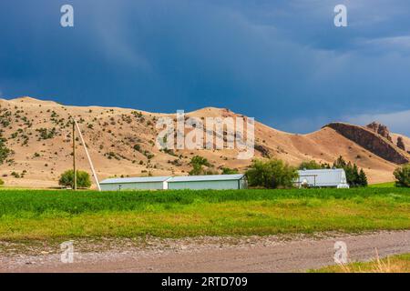 Light Before a Storm auf Farmen im Südwesten von Montana mit der Gallatin-Bergkette und dem Nationalwald in der Ferne. Getreide- und Heuanbau. Stockfoto