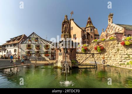 Brunnen Fontaine de Saint-Léon und St.-Leo-Kapelle in Eguisheim, Elsass, Frankreich | Fontaine de Saint-Léon und Chapelle Saint-Léon in EG Stockfoto