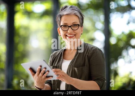 Glückliche Freiberuflerin im mittleren Alter mit digitalem Tablet Stockfoto