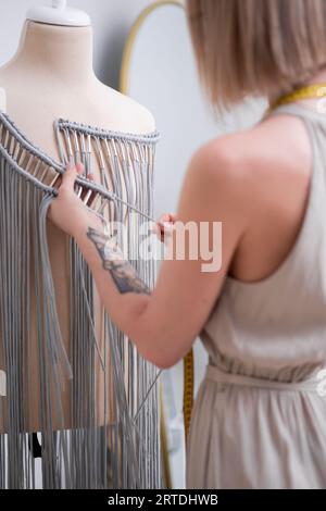 Makramee-Kleid mit grauen Fäden in Kunsthandwerkswerkstatt, kreativer Schneiderin Stockfoto