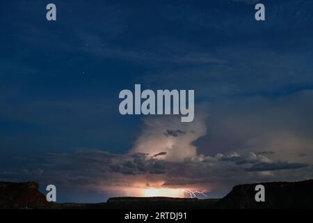 Ein blauer Blitz streift über einen unheilvollen grauen Himmel und beleuchtet die verstreuten Wolken Stockfoto