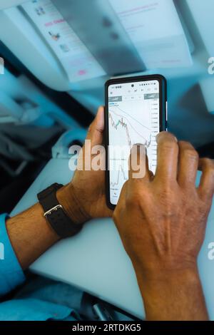 Mann, der den Devisenmarkt auf dem Smartphone überprüft. Mobile Stock Phone-Anwendung. Finanzbörse und -Handel. Händler, der Smartphone mit Börseneinsätzen verwendet Stockfoto