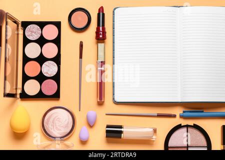 Komposition mit Make-up-Kosmetik und Notizbuch auf beigem Hintergrund Stockfoto