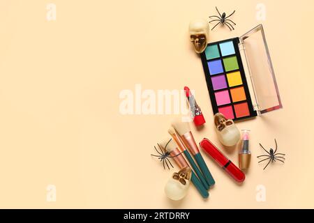 Lippenstifte und verschiedene dekorative Kosmetik mit Halloween-Dekor auf beigem Hintergrund Stockfoto