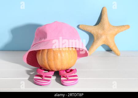 Halloween Kürbis mit Strandaccessoires und Seesternen auf hellem Holztisch Stockfoto