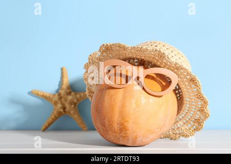 Halloween Kürbis mit Strandaccessoires und Seesternen auf hellem Holztisch Stockfoto