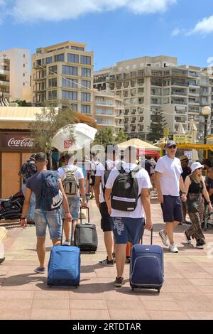 Sliema, Malta - 6. August 2023: Jugendliche ziehen Koffer an der Promenade von Sliema. Stockfoto