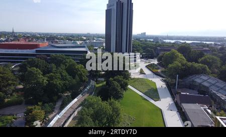 Botanischer Garten : Planten un blomen in Hamburg und Wolkenkratzer (vielleicht Hotel) und Aussen-Alster in der Ferne - Stadtbild im Sommermorgen Stockfoto