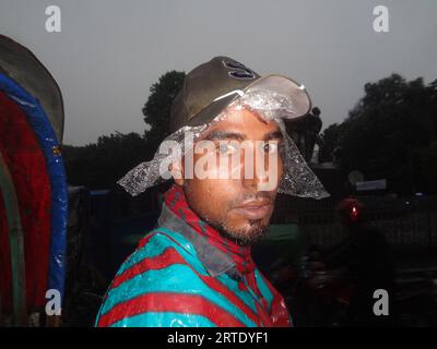 Dhaka, Bangladesch. September 2023. Ein Rikscha-Abzieher reagiert auf die Kamera, da er mit einer Plastikfolie bedeckt ist, um Regen in Dhaka zu vermeiden. (Bild: © MD Mehedi Hasan/ZUMA Press Wire) NUR REDAKTIONELLE VERWENDUNG! Nicht für kommerzielle ZWECKE! Stockfoto