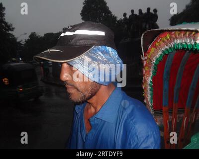 Dhaka, Bangladesch. September 2023. Ein Rikscha-Abzieher bedeckte seinen Kopf mit einer Plastikfolie, um Regen in Dhaka zu vermeiden. (Bild: © MD Mehedi Hasan/ZUMA Press Wire) NUR REDAKTIONELLE VERWENDUNG! Nicht für kommerzielle ZWECKE! Stockfoto