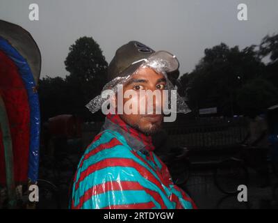 Dhaka, Bangladesch. September 2023. Ein Rikscha-Abzieher reagiert auf die Kamera, da er mit einer Plastikfolie bedeckt ist, um Regen in Dhaka zu vermeiden. (Bild: © MD Mehedi Hasan/ZUMA Press Wire) NUR REDAKTIONELLE VERWENDUNG! Nicht für kommerzielle ZWECKE! Stockfoto