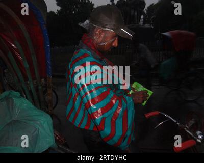 Dhaka, Bangladesch. September 2023. Ein Rikscha-Abzieher, der mit einer Plastikfolie bedeckt ist, um Regen in Dhaka zu vermeiden. (Bild: © MD Mehedi Hasan/ZUMA Press Wire) NUR REDAKTIONELLE VERWENDUNG! Nicht für kommerzielle ZWECKE! Stockfoto