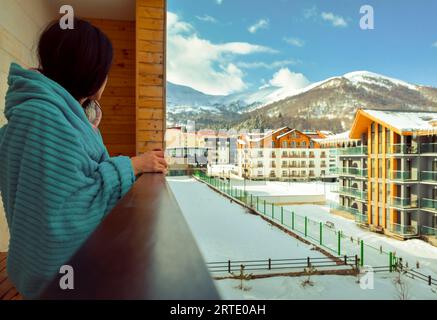 Bakuriani, Georgien - 5.. März 2022: Weibliche kaukasische Touristen am Morgen trinken Kaffee auf dem Balkon in Ferienwohnung Gebäude auf Bakuriani Urlaub s Stockfoto
