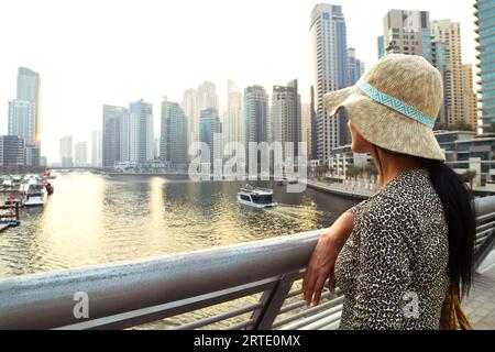 Dubai, VAE - 12.. oktober 2022: Wunderschöne kaukasische Touristenfrau in modischem Sommerkleid Genießen Sie den Yachthafen von Dubai in den Vereinigten Arabischen Emiraten. Luxus und Stockfoto