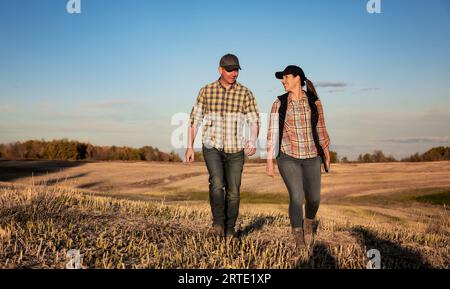 Ein Mann und eine Frau, die auf einem Feld stehen, verbringen einige Zeit zusammen, nachdem sie ihren Fall, Rapsernte, vollzogen haben Stockfoto