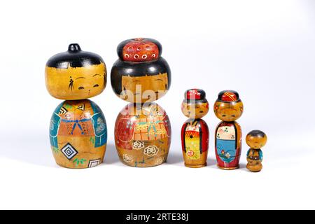 Vintage japanisch bemalte Holzblattkopf Kokeshi Folk Puppen Gruppe isoliert vor einem weißen Studio Hintergrund Nesting Stockfoto