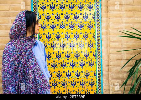 Kashan, Iran - 27. Mai 2022: Touristische Standposition für Social-Media-Fotos in der Öffentlichkeit an der Wand mit Ornamenten im traditionellen persischen Fin-Garten Kashan, IR Stockfoto