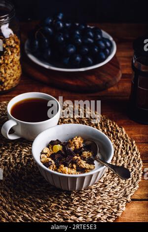 Hausgemachtes Granola mit getrockneten Früchten und Schokolade in Vintage Bowl und Tasse Kaffee zum Frühstück Stockfoto
