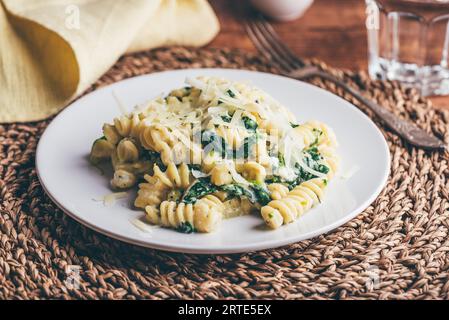 Fusilli Pasta mit Spinat und Ricotta garniert mit geriebenem Parmesan Käse auf weißem Teller Stockfoto
