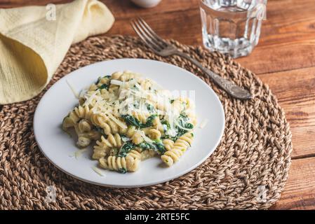 Fusilli Pasta mit Spinat und Ricotta garniert mit geriebenem Parmesan Käse auf weißem Teller Stockfoto