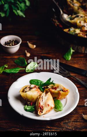 Gebackene Jumbo Shells Pasta gefüllt mit Hackfleisch, Spinat und Käse auf weißem Teller Stockfoto