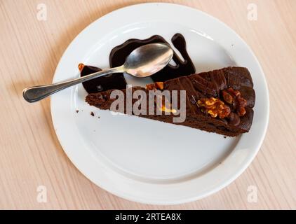 Süßes, zartes dreieckiges Stück Schokoladen-Nuss-Kuchen, mit flüssiger Schokolade gefüllt, auf Teller serviert Stockfoto