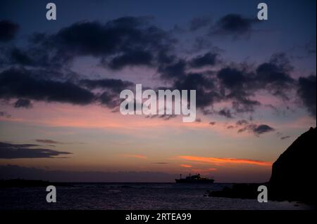 Silhouette eines Kreuzfahrtschiffes bei Sonnenuntergang in der Nähe der Insel San Cristobal im Nationalpark der Galapagos Islands; San Cristobal Island, Galapagos Islands, Ecuador Stockfoto