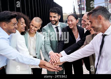 Multikulturelles, glückliches Team für die Teambildung in der Geschäftsgruppe, das Hand in Hand geht. Lächelnder, vielseitiger Profi. Stockfoto