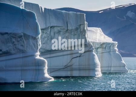 Nahaufnahme eines großen Eisbergs mit silbrigen Streifen, die im eisblauen Wasser des Kaiser-Franz-Joseph-Fjords Grönlands schweben; Ostgrönland, Grönland Stockfoto