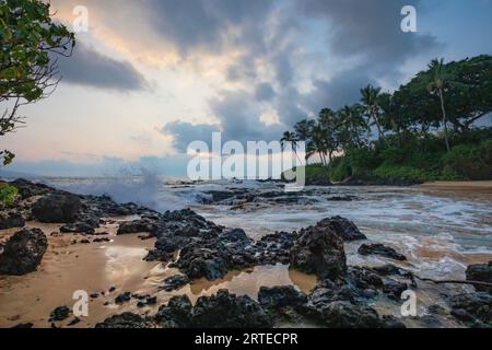 Secret Beach mit Palmen und Meeressurfen am Ufer von Makena Cove; Maui, Hawaii, Vereinigte Staaten von Amerika Stockfoto