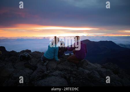 Familie auf einem Berggipfel über den Wolken von Haleakala und beobachten den Sonnenaufgang über der Pazifikküste Stockfoto
