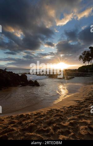 Sonnenstrahlen reflektieren auf dem Wasser am Secret Beach mit Blick auf die Bucht und den Pazifischen Ozean in der Dämmerung, während eine Person ein Foto entlang der... Stockfoto