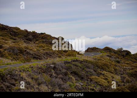 Malerische Aussicht auf eine scharfe Kurve auf dem Mountain Highway mit Blick auf die Wolken über dem Berghang auf der Road Down von Haleakala Stockfoto