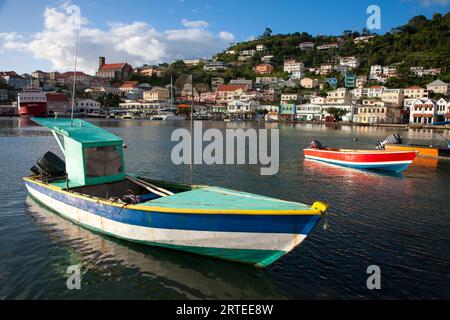 Hafenszene mit farbenfrohen Fischerbooten, die an einem sonnigen Tag in der Nähe der Küste und der Hafenstadt St. Georges im Hintergrund liegen Stockfoto