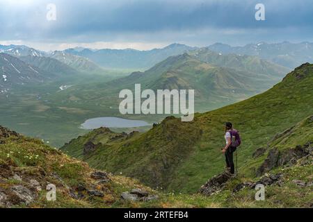 Frau, die auf einer Bergseite mit Blick auf das Upper Blackstone Valley im Norden von Yukon steht und die wunderschöne Aussicht entlang des Dempst genießt... Stockfoto