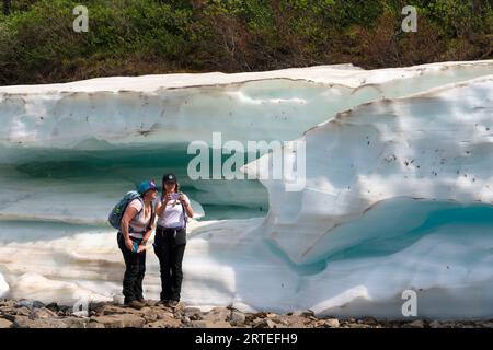Nahaufnahme von zwei Frauen, die ein Selfie erforschen und machen, die neben der Eisformation der Spätsaison stehen, bekannt als Aufeis (erstellt durch mehrere Schichten von... Stockfoto