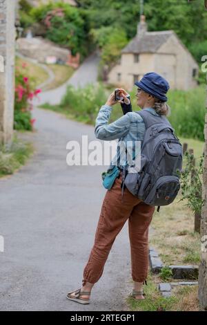 Reife Frau nutzt ihr Smartphone auf Reisen im Freien; Großbritannien Stockfoto