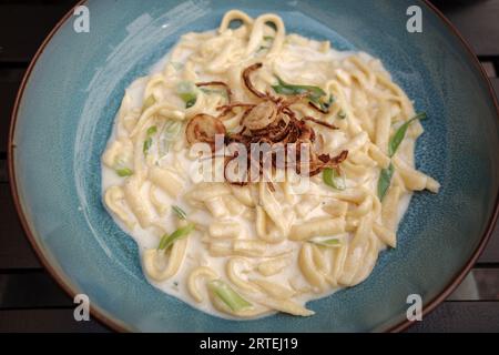 Blick von oben, Käse-Spätzle, Käsespätzle. Mit Pilzen, Sahnesauce und gebratenen Zwiebeln. Stockfoto