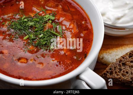 Soljanka mit Sauerrahm und Kräutern auf einem Holzbrett Stockfoto