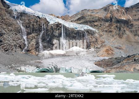 Schmelzender Fellaria-Gletscher im Berg, hoher Wasserfallhintergrund, Eisspalten, See mit Eisbergen im Vordergrund. Globale Erwärmung und Klimawandel Stockfoto