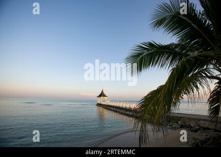 Das Meer umgibt einen Pavillon und einen Pier bei Sonnenuntergang in einem Resort in Jamaika; Jamaika Stockfoto