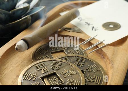 Akupunkturnadeln, Moxa-Stick und antike chinesische Münzen auf Holztablett, Nahaufnahme Stockfoto