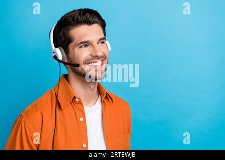 Porträt einer positiven, fröhlichen Person, die lächelnd kommuniziert Kunden Headset-Look Leere Platz Anzeige isoliert auf blauem Hintergrund Stockfoto