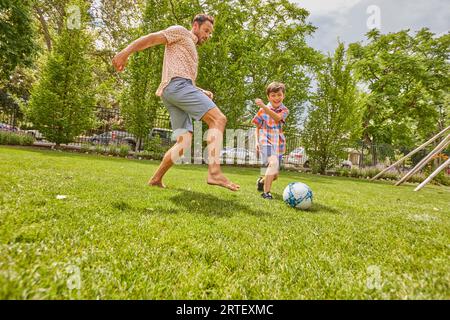 Vater und Sohn (8-9) spielen Fußball im Park Stockfoto