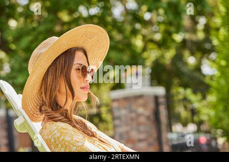 Frau mit Strohhut und Sonnenbrille, die sich im Park entspannt Stockfoto