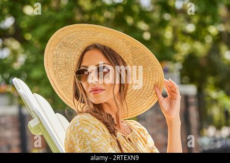 Frau mit Strohhut und Sonnenbrille, die sich im Park entspannt Stockfoto