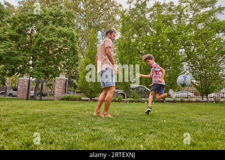 Vater und Sohn (8-9) spielen Fußball im Park Stockfoto