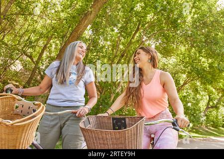 Mutter und Erwachsene Tochter fahren im Park mit dem Fahrrad Stockfoto